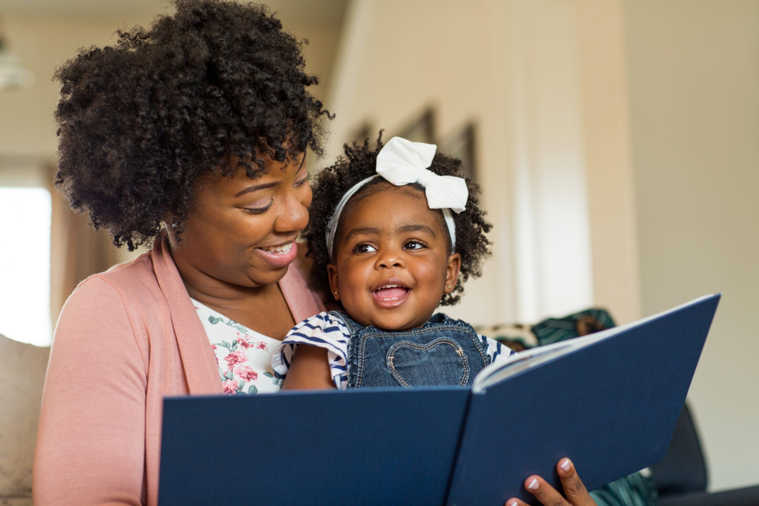 Image of black woman reading to a very happy child.