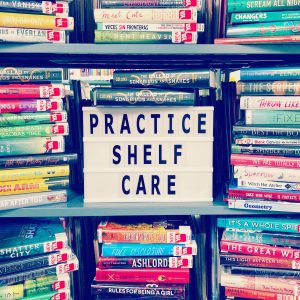 Piles of books surrounding a sign that reads "Practice Shelf Care"