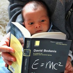image description: adult holding a small infant with a book that title includes the text 'e = m c squared"