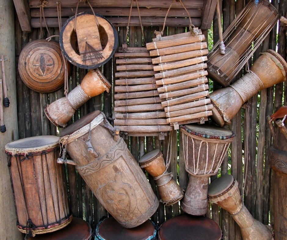 Image description of a rustic wooden wall with several wooden drums and two wooden xylophones hanging from it.