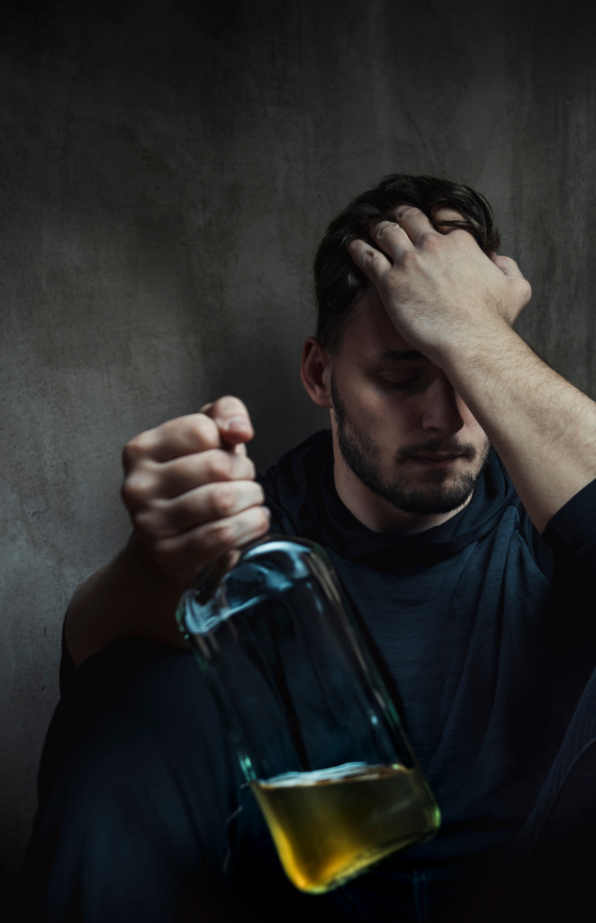 image of a man holding an alcohol bottle looking sad